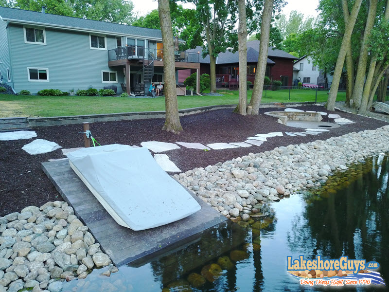 Reycled plastic boat ramp with riprap shoreline, stone walkway, and fire pit