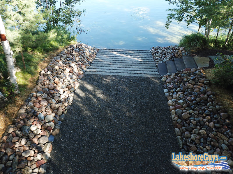 Segmented concrete boat ramp with long gravel path, riprap shoreline, and staircase